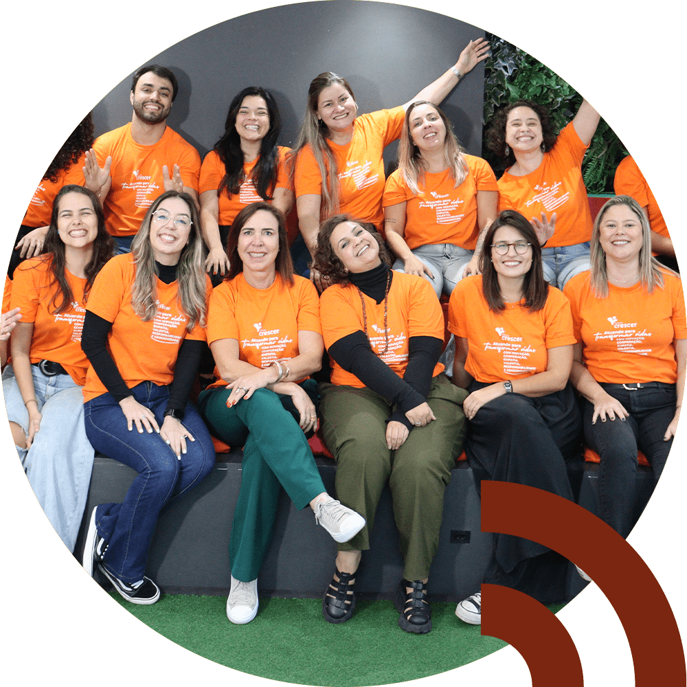 Grupo colaboradores do Crescer vestindo camisetas laranjas e sorrindo.